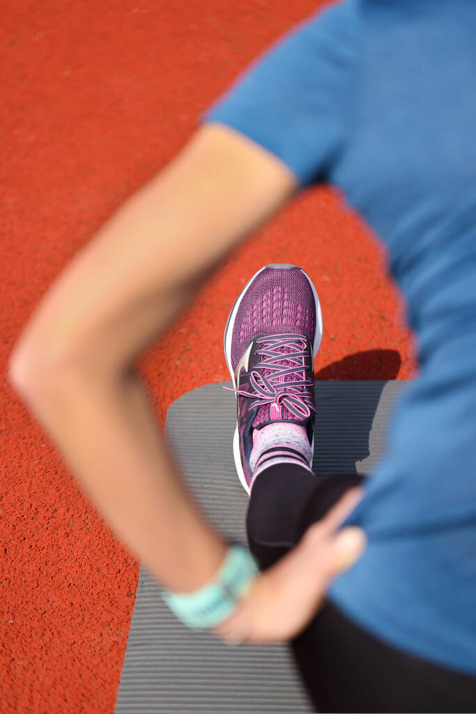 Vertikální pohled na ženu ve sportovním oblečení cvičit jógu cvičení v tělocvičně na oranžové podlaze pozadí - Fotografie, Obrázek