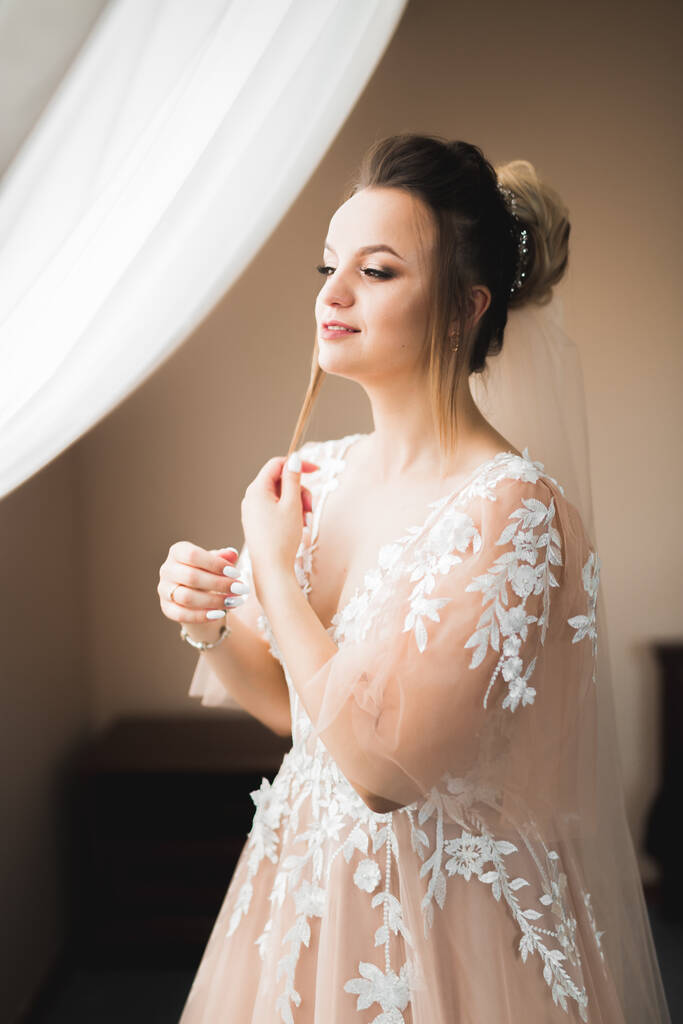 Novia de lujo en vestido blanco posando mientras se prepara para la ceremonia de boda. - Foto, Imagen