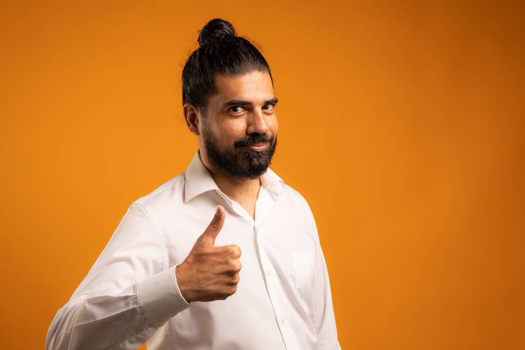 Una bella foto di un uomo ispanico che mostra emozioni davanti a uno sfondo arancione - Foto, immagini
