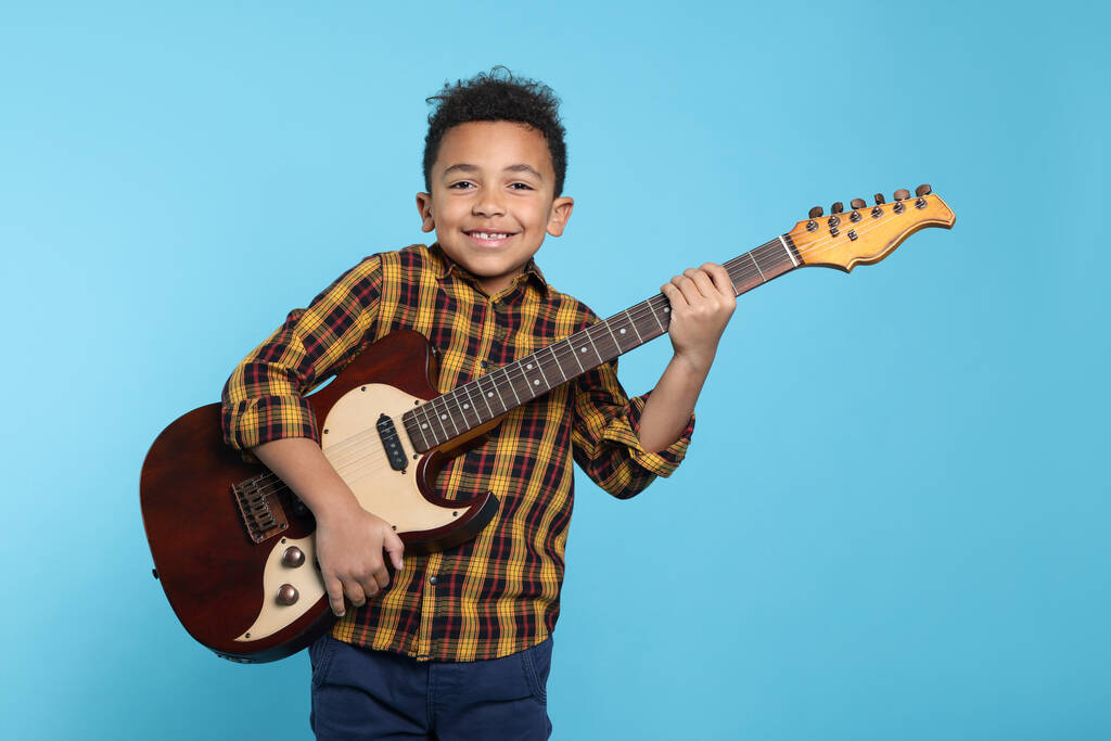 Turkuaz arka planda elektro gitarı olan sevimli Afro-Amerikalı çocuk. - Fotoğraf, Görsel