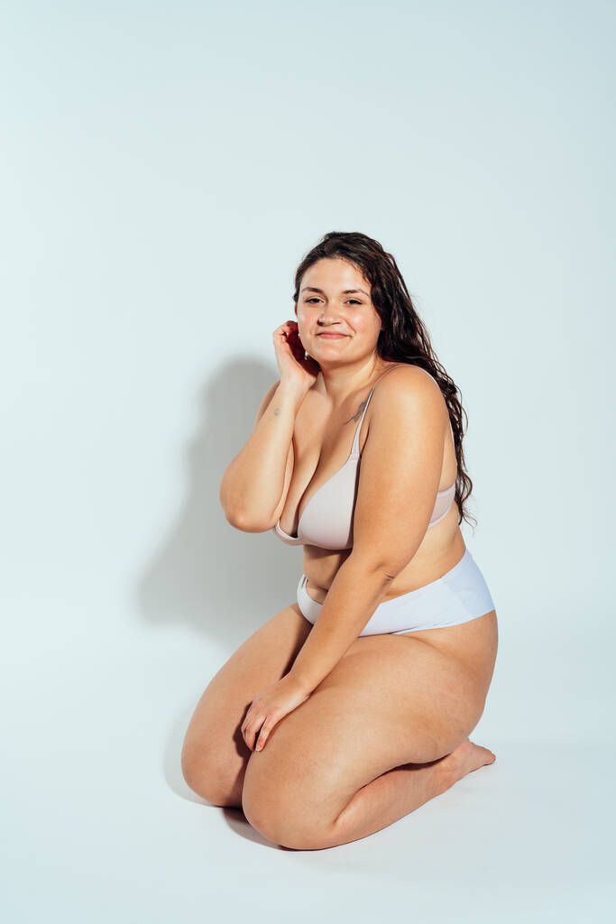 Plus size donna in posa in studio in lingerie. Modello su sfondo bianco. Hard light studio girato - Foto, immagini