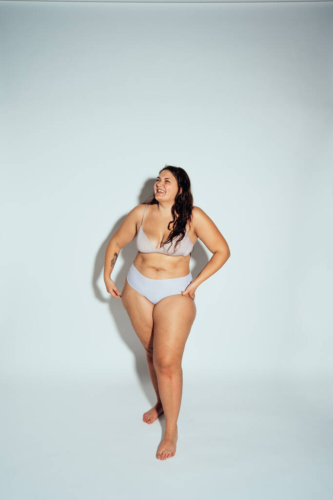 Plus velikost ženy pózující ve studiu ve spodním prádle. Model na bílém pozadí. Tvrdé světlo studio shot - Fotografie, Obrázek
