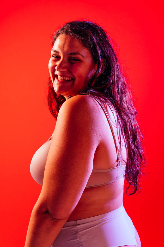 Plus grootte vrouw poseren in de studio in lingerie. Model op gekleurde achtergrond. Harde licht studio opname - Foto, afbeelding