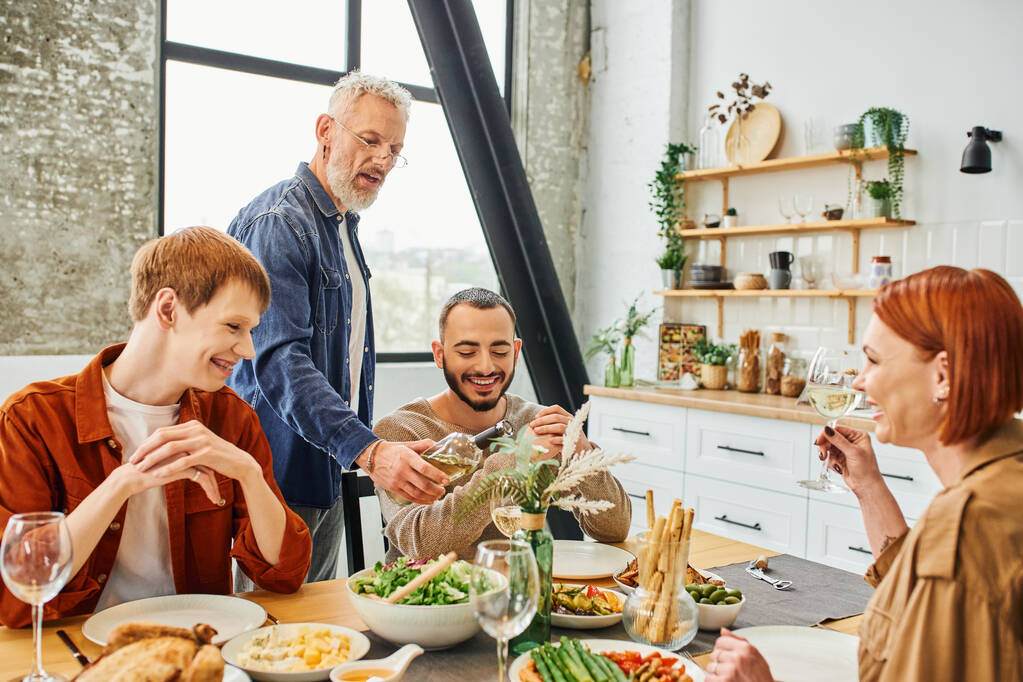 parrakas mies näyttää viinipullo iloinen homo pari aikana perheen illallinen moderni keittiö - Valokuva, kuva