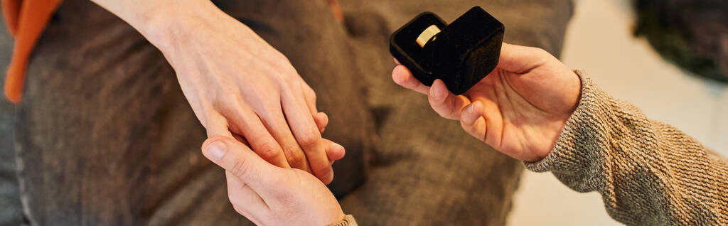częściowy widok gej człowiek gospodarstwa biżuteria pudełko z obrączka i trzymając ręka z chłopak podczas dokonywania ślub oświadczyny, baner - Zdjęcie, obraz