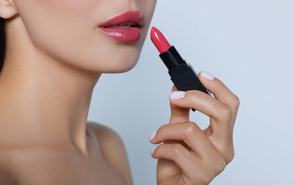 Jonge vrouw met mooie make-up met glanzende lippenstift op lichtgrijze achtergrond, close-up - Foto, afbeelding