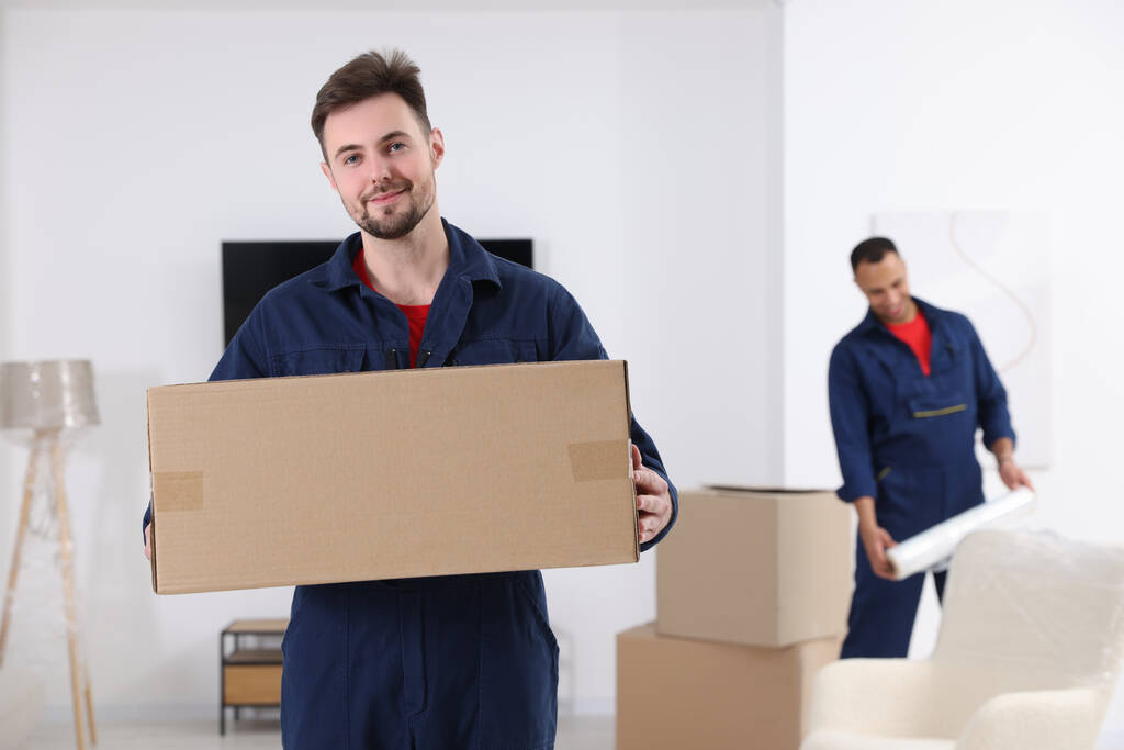 Muž pohybující se s kartonovou krabicí v domě, prostor pro text - Fotografie, Obrázek