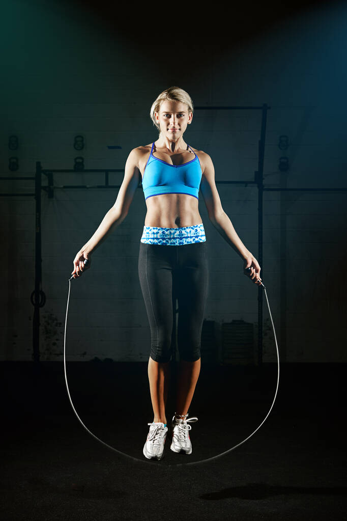 Evite su camino a un estilo de vida más saludable. una joven saltando la cuerda en un gimnasio - Foto, imagen