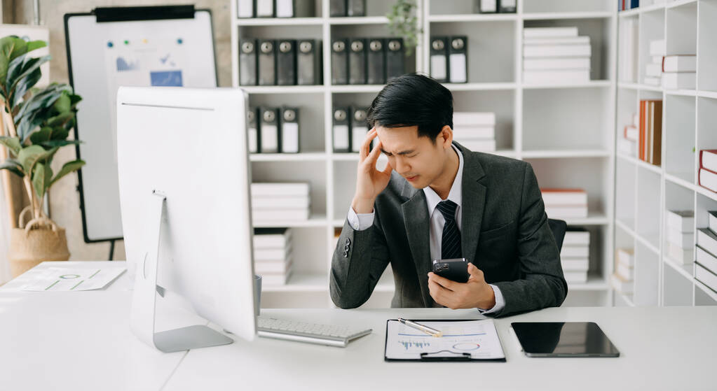 Empresario asiático está estresado, aburrido, y pensando en exceso de trabajar en la computadora en la oficina moderna. - Foto, imagen