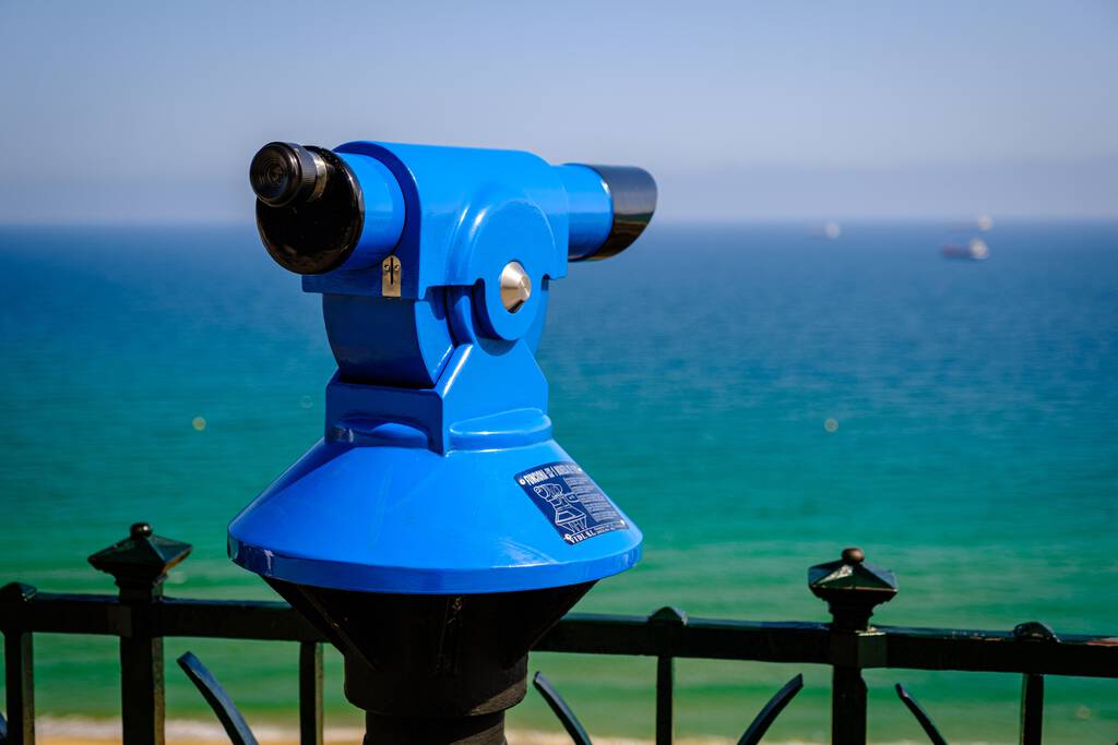 Um telescópio público azul na costa, para uso turístico, com uma paisagem azul-turquesa ao fundo, num dia ensolarado - Foto, Imagem