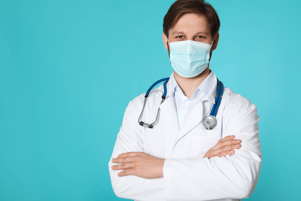 Доктор або медичний асистент (чоловіча медсестра) з захисною маскою та стетоскопом на бірюзовому тлі. Простір для тексту
 - Фото, зображення