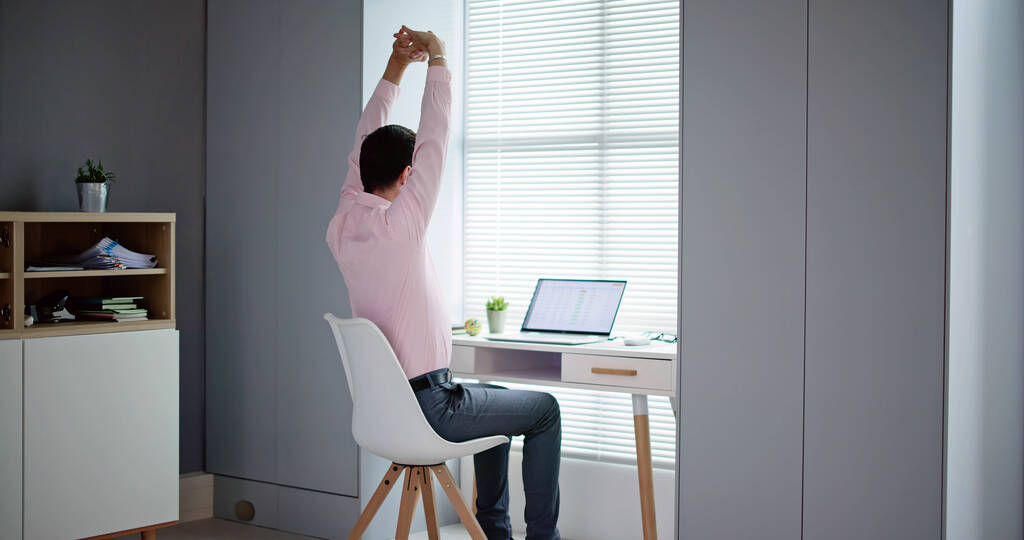 Jovem empresário feliz esticando seus braços no escritório
 - Foto, Imagem