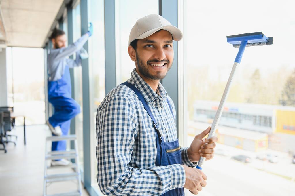 Conserje masculino limpiando ventana en la oficina
. - Foto, Imagen