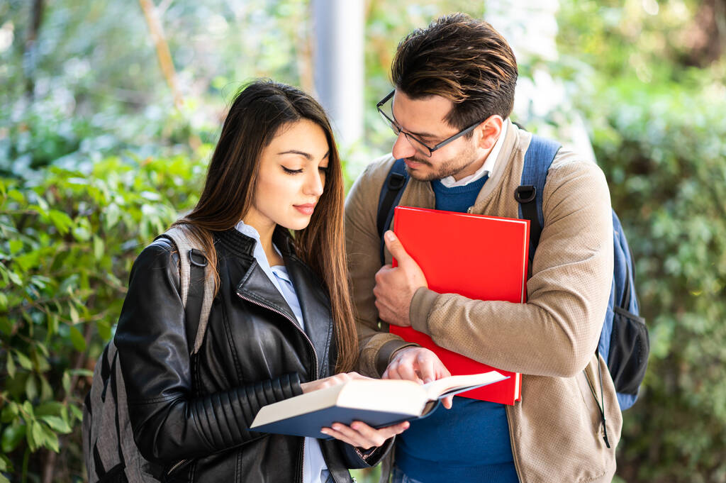 Two students, male and female, talking outdoors holding books - Photo, Image