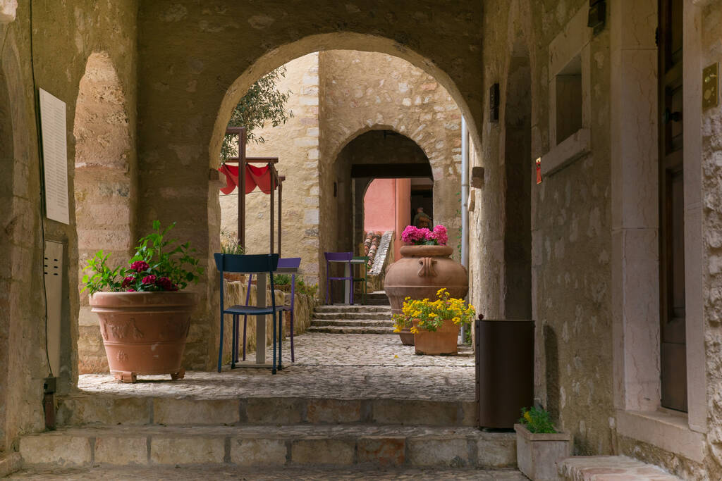 CASTELLO DI POSTIGNANO, ITALIA - 30 DE ABRIL DE 2023: Arcos en el centro antiguo de Postignano con sillas de colores en la región de Umbría, Italia - Foto, imagen