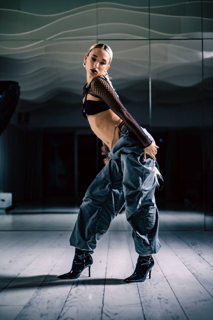 Вертикальний вигляд привабливої танцівниці Стільто, що позує перед дзеркалом в студії
 - Фото, зображення