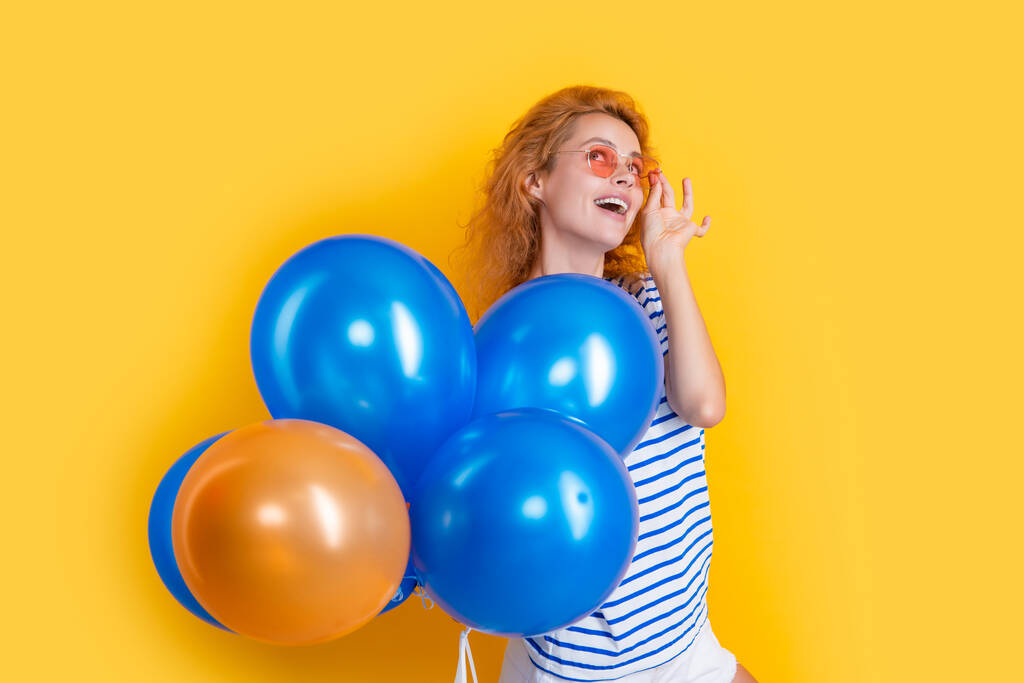 feestbeest met ballon in zonnebril. Gelukkig meisje houdt helium ballonnen in de studio. meisje met ballon voor partij geïsoleerd op gele achtergrond. - Foto, afbeelding