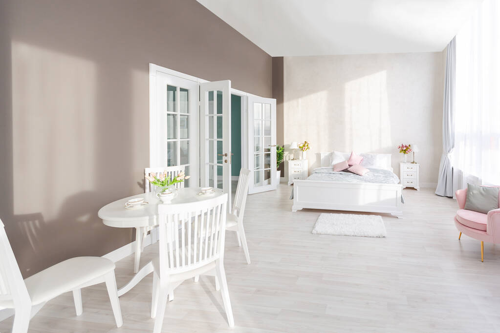 Lujoso y caro interior de un apartamento de planta abierta en colores claros. Elegante dormitorio moderno con diseño minimalista, comedor y espacio para invitados. - Foto, imagen
