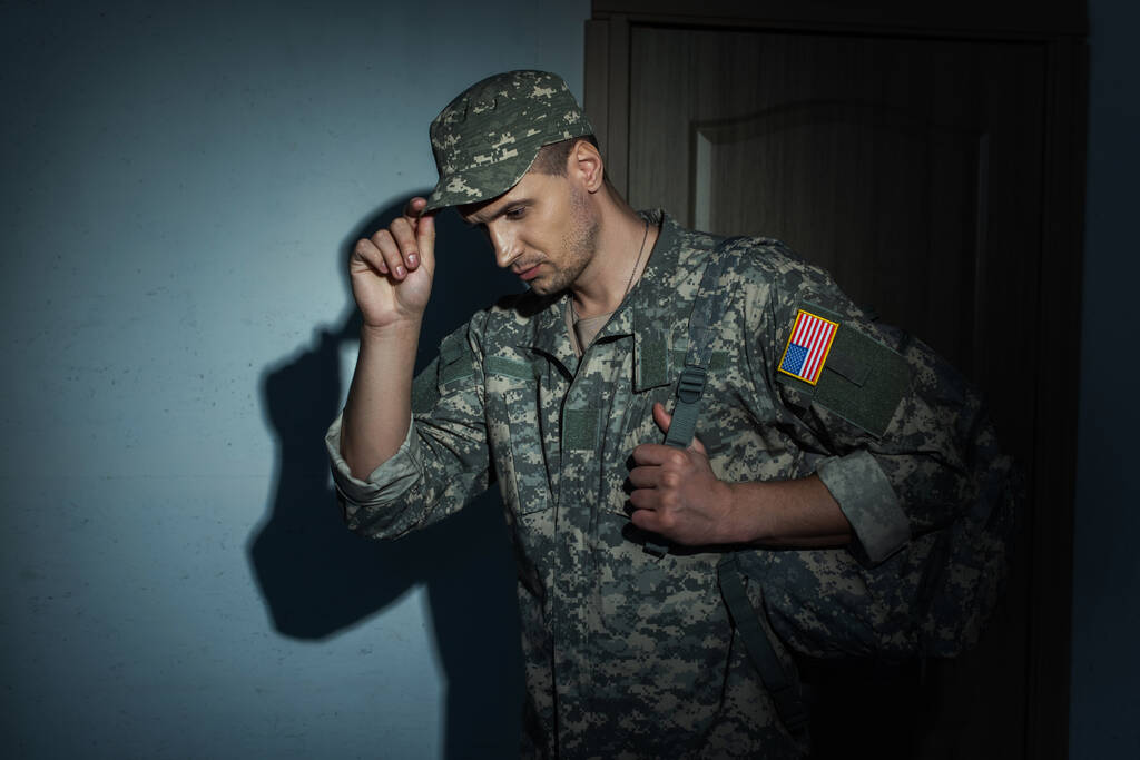 Militar americano quitándose la gorra mientras vuelve a casa por la noche - Foto, imagen