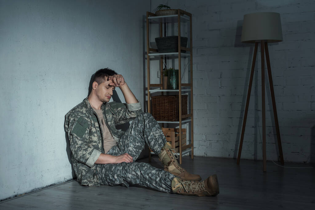 Eve dönüşünden sonra travma sonrası stres bozukluğu olan hayal kırıklığına uğramış bir asker yerde oturuyor.  - Fotoğraf, Görsel