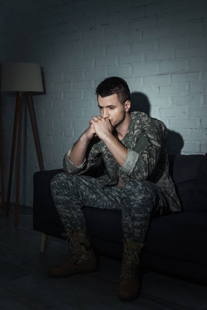 Turhautunut sotilas naamioituneena istuu sohvalla ja kärsii ptsd kotona - Valokuva, kuva