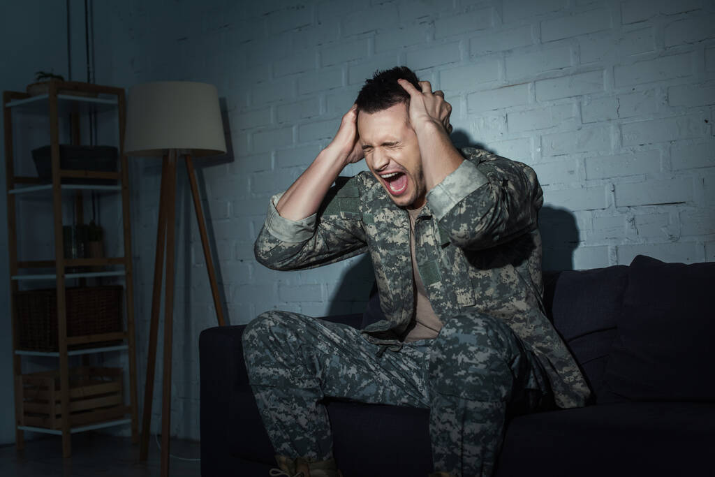 Veterano militar irritado gritando enquanto sofre de sofrimento emocional em casa à noite  - Foto, Imagem