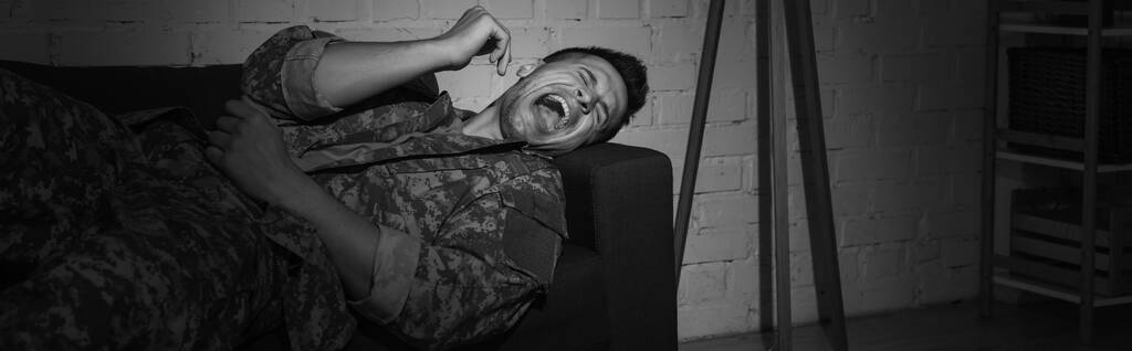 zwart-wit foto van bezorgde soldaat schreeuwen terwijl hij lijdt aan post traumatische stress stoornis, spandoek  - Foto, afbeelding