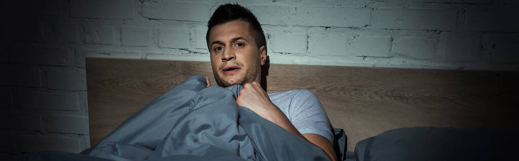 homem estressado com ataques de pânico tendo insônia enquanto deitado sob cobertor, banner   - Foto, Imagem