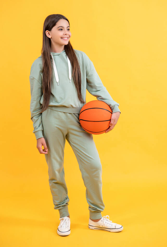 повна довжина дівчинки-підлітка баскетболу ізольована на жовтому. дівчина з баскетболу в студії. дівчина з баскетболу на фоні. фото дівчини-підлітка з м'ячем
. - Фото, зображення
