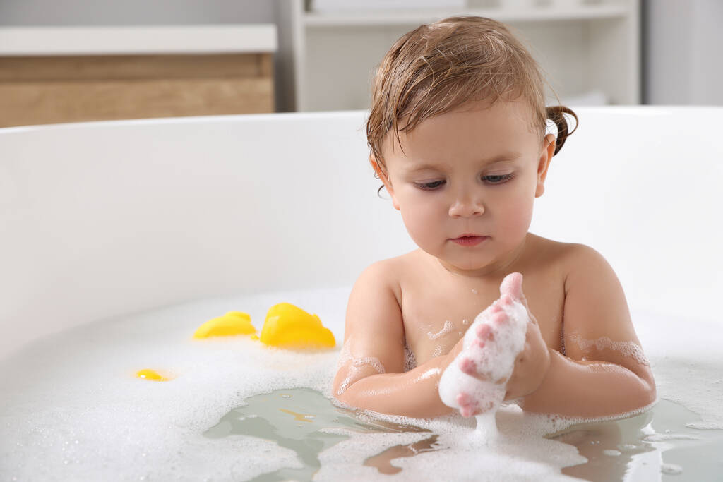 Мила дівчинка приймає пінисту ванну вдома
 - Фото, зображення