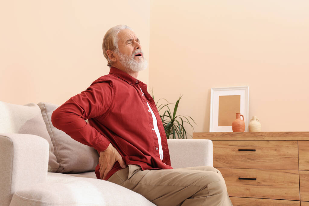 Hombre mayor sufriendo de dolor en su espalda en casa. Síntomas de artritis - Foto, imagen