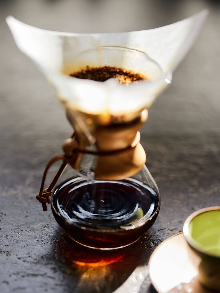 Um close-up vertical de café pingando através de um filtro de papel sobre uma xícara - Foto, Imagem