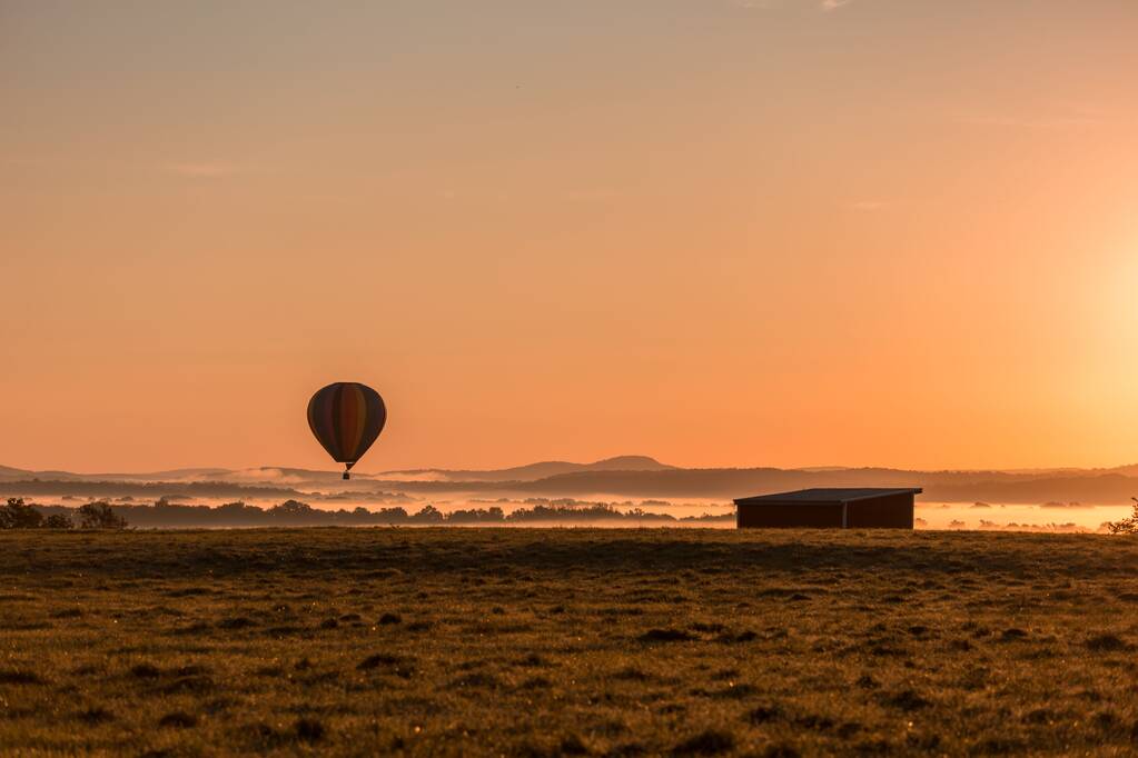 Egy gyönyörű felvétel egy hőlégballonról, ami egy ködös völgyben lebeg naplementekor. - Fotó, kép