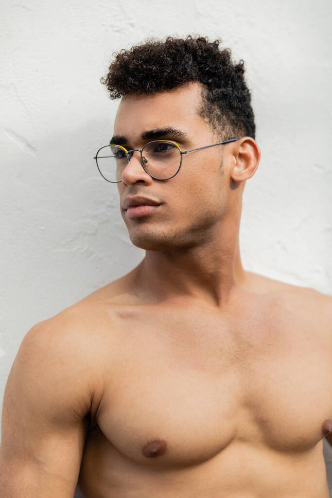 Portrait de jeune homme cubain torse nu et musclé avec des lunettes rondes élégantes détournant les yeux - Photo, image