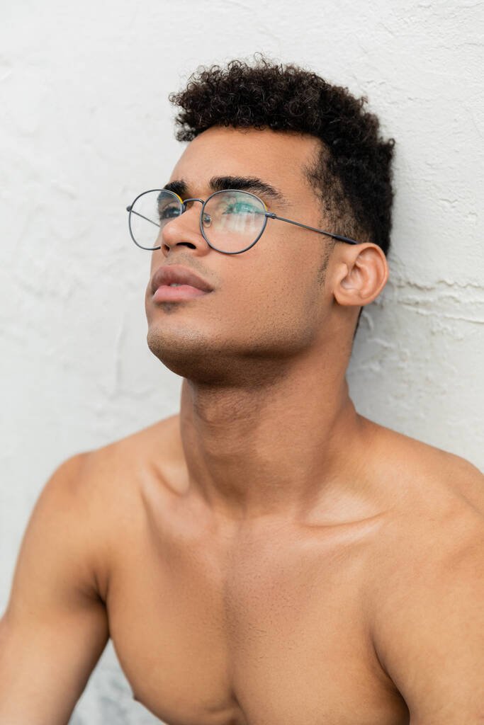 Retrato de homem cubano jovem muscular sem camisa com cabelo encaracolado e óculos em forma de redondo elegantes - Foto, Imagem