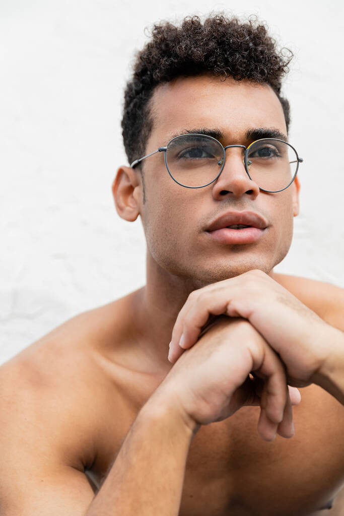 Portrait of shirtless cuban man in round-shaped eyeglasses with curly hair looking away - Photo, Image