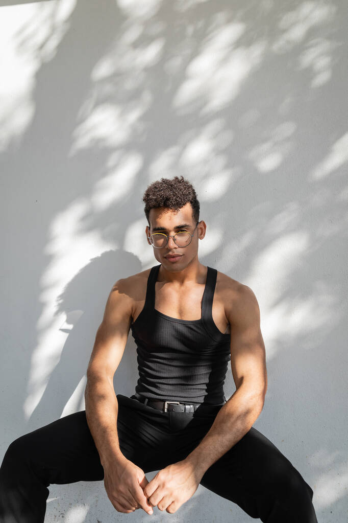 Rilassato ed elegante, muscoloso e giovane cubano in abito nero e occhiali  - Foto, immagini