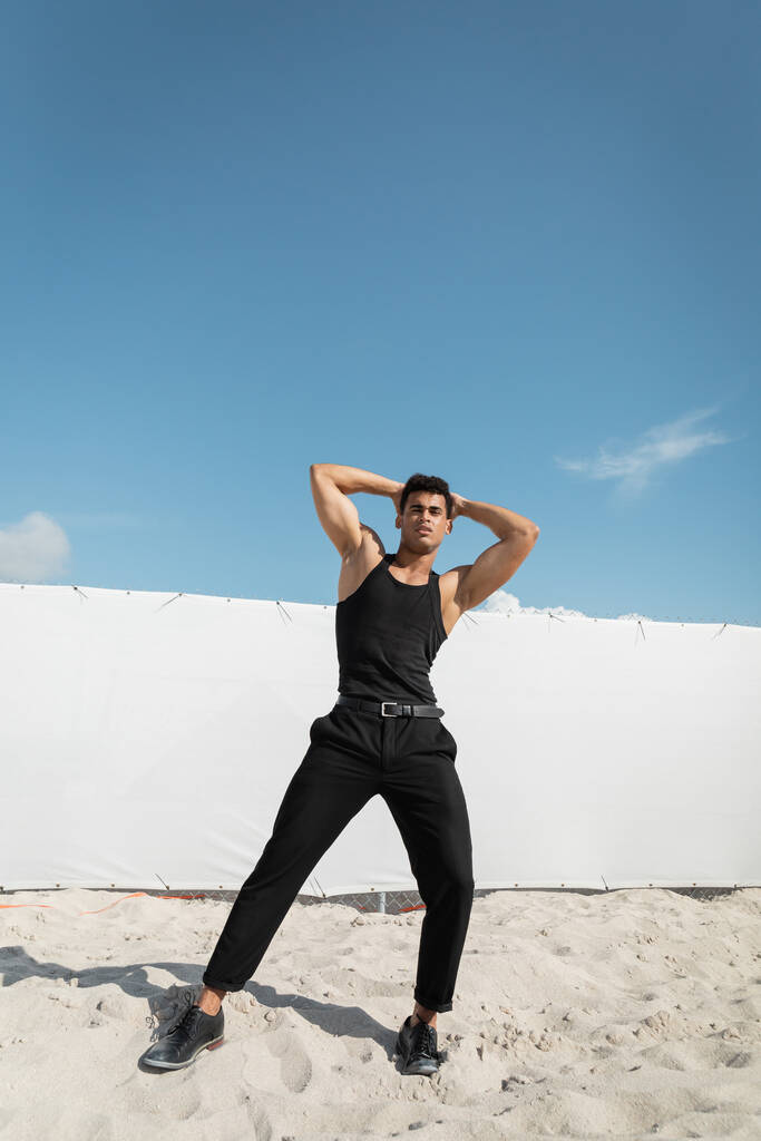 Hombre cubano fuerte y joven en traje negro tocando la cabeza y mirando a la cámara en Miami, playa sur - Foto, Imagen