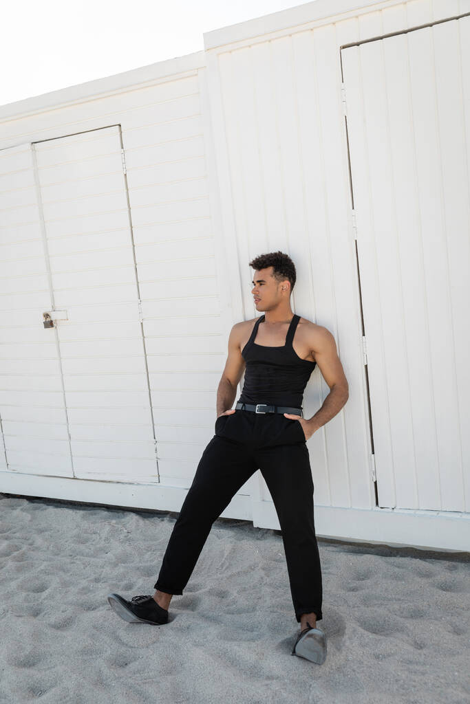 南のビーチ,マイアミのポケットに手を握るスタイリッシュな黒い服でリラックスした筋肉の立方体男性 - 写真・画像