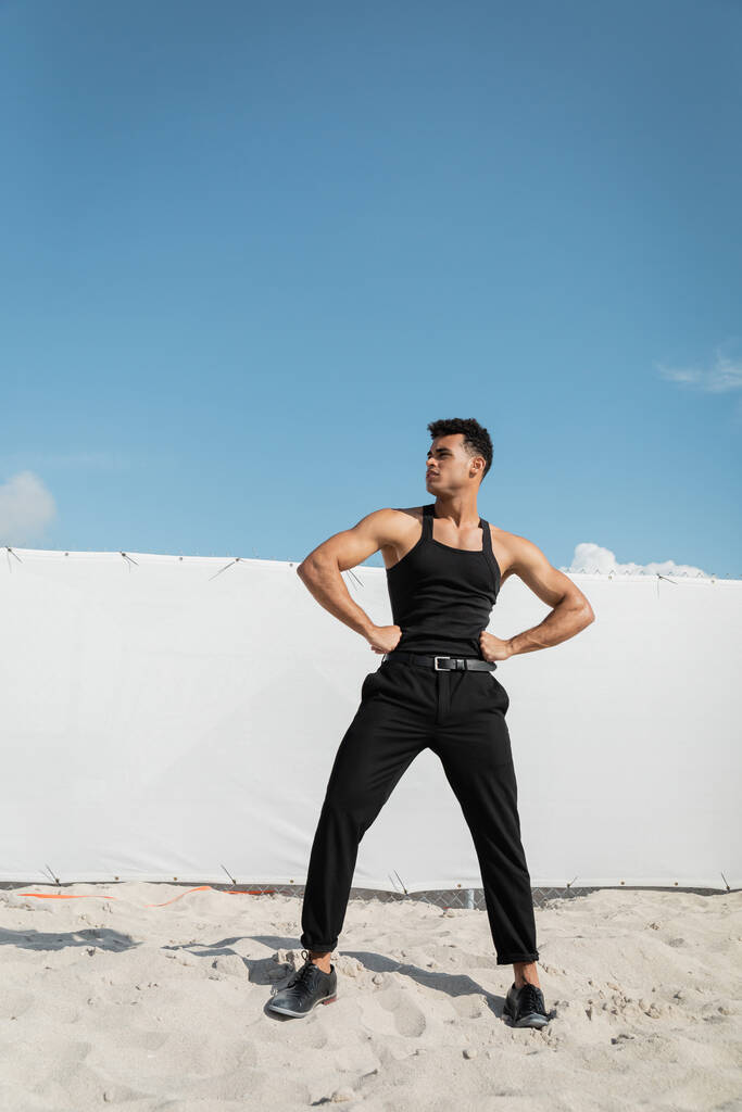 Hyvännäköinen ja lihaksikas nuori kuubalainen mies mustassa ja tyylikkäässä asussa Miamissa, etelärannalla - Valokuva, kuva