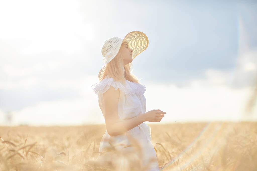 Καυκάσια γυναίκα με καπέλο ποζάροντας στον αγρό σιταριού κατά τη διάρκεια της ημέρας - Φωτογραφία, εικόνα