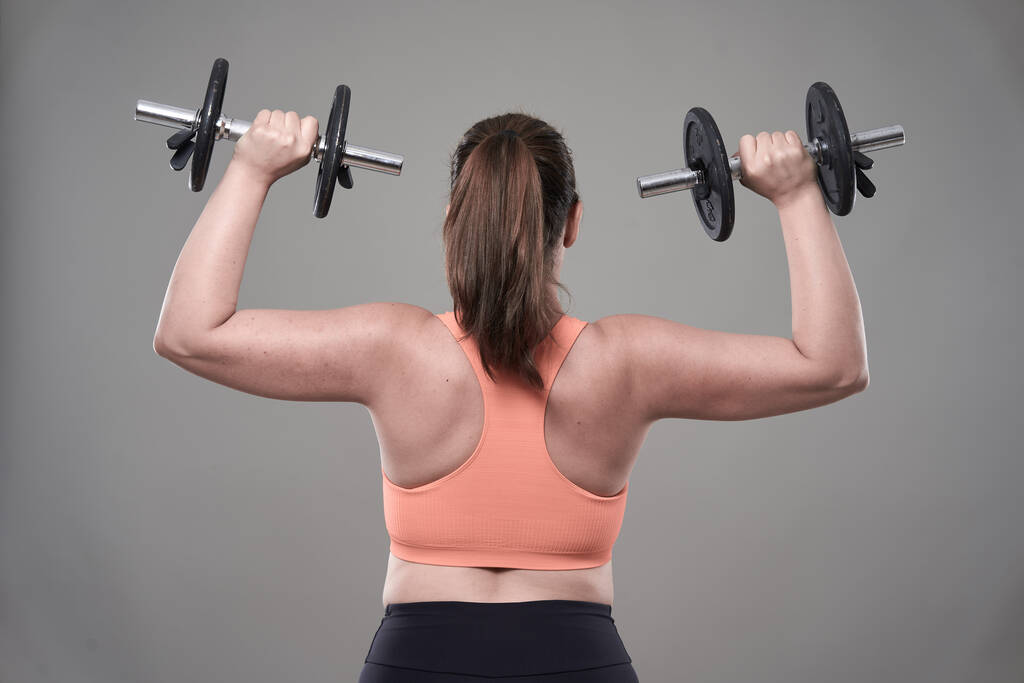 Fuerte confianza más tamaño mujer joven ejercitando ejercicios de fitness con pesas - Foto, Imagen