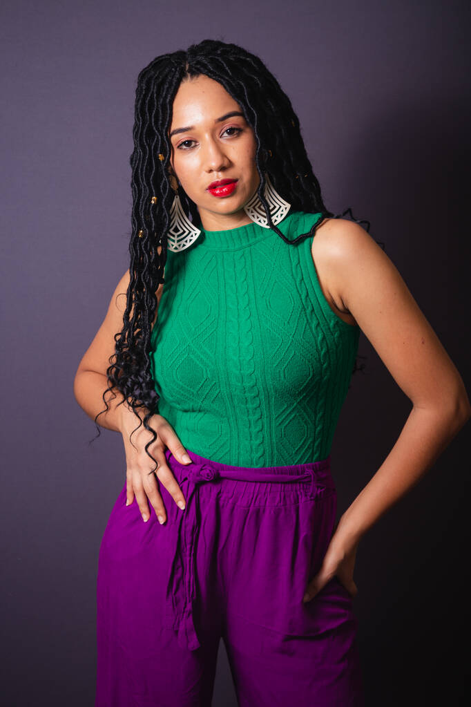 緑と紫の服を着た美しいブラジルの黒人女性。半体の肖像画、灰色の無限大の背景. - 写真・画像