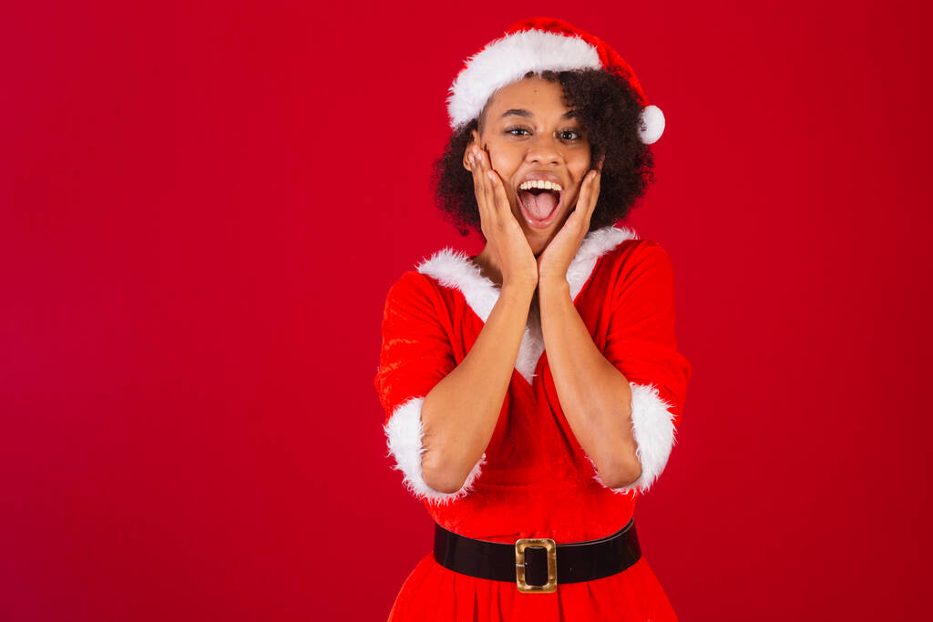 beautiful black brazilian woman, dressed as santa claus, mama claus, hands on face, incredible - Photo, Image
