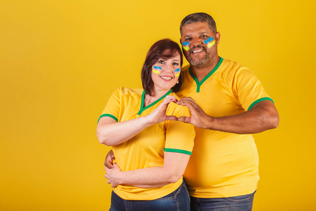 Пара рудоволосих жінок і чорношкірих, бразильські футбольні фанати. знак серця. - Фото, зображення