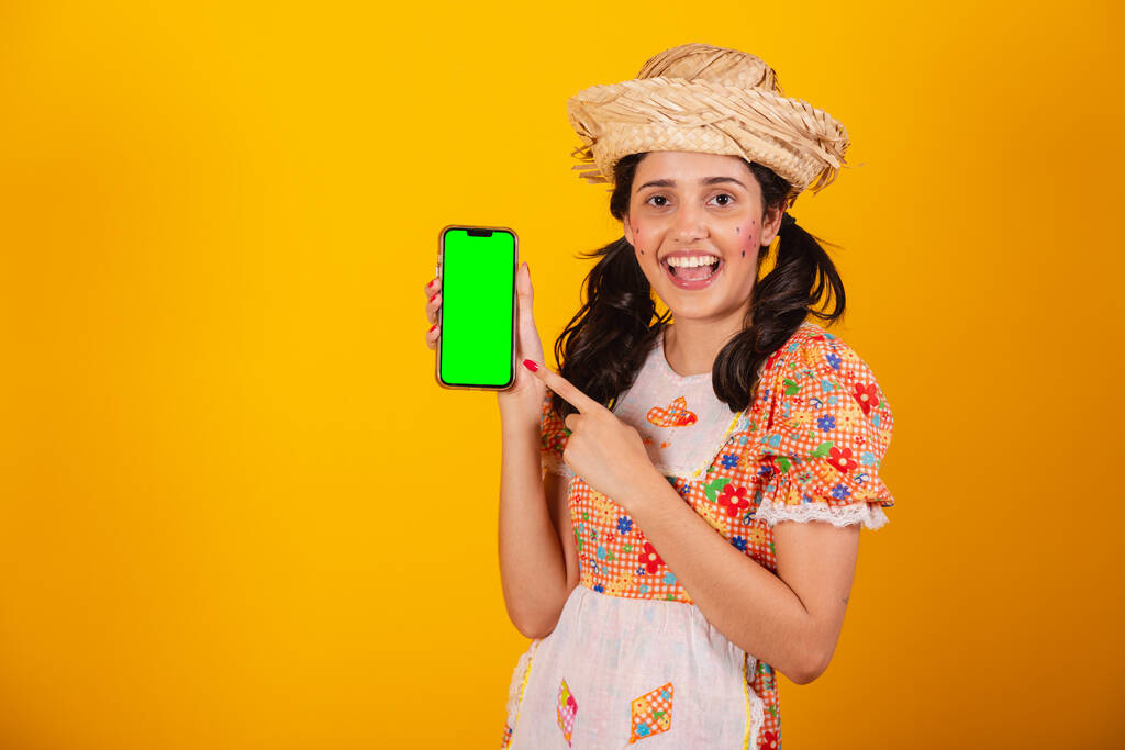Krásná brazilská žena, s festa junina oblečení, drží smartphone se zelenou obrazovkou. - Fotografie, Obrázek