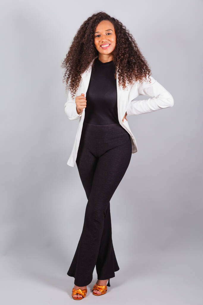 függőleges fotó, gyönyörű fekete brazil nő, üzletasszony, fehér öltönyt visel, mosolyog, optimista. - Fotó, kép