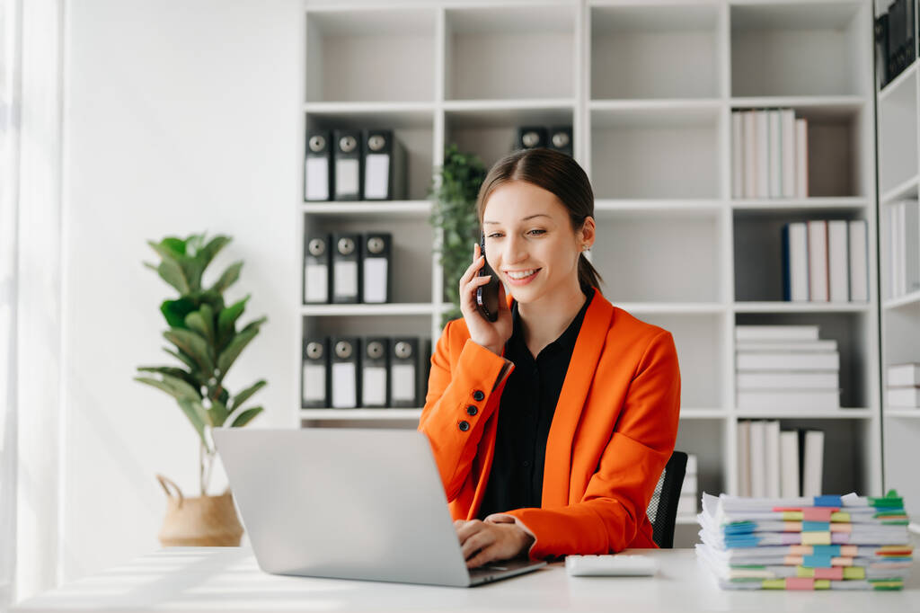 Businesswoman caucasico Parlare al telefono e utilizzando un computer portatile in ufficio moderno - Foto, immagini