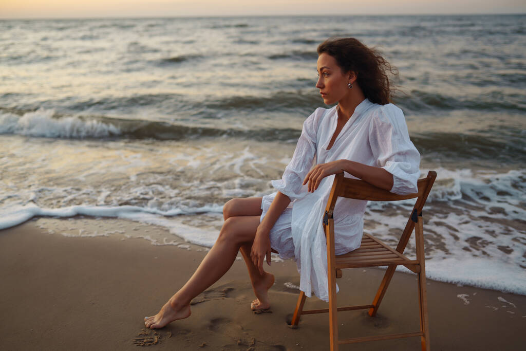 La jeune femme profite d'un incroyable lever de soleil sur la plage. Mode, concept de style. Personnes, style de vie, détente et concept de vacances. - Photo, image