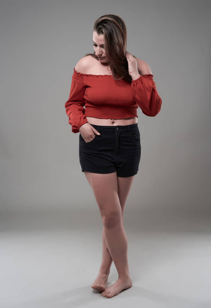 Studioporträt einer selbstbewussten Plus-Size-jungen Frau auf grauem Hintergrund - Foto, Bild